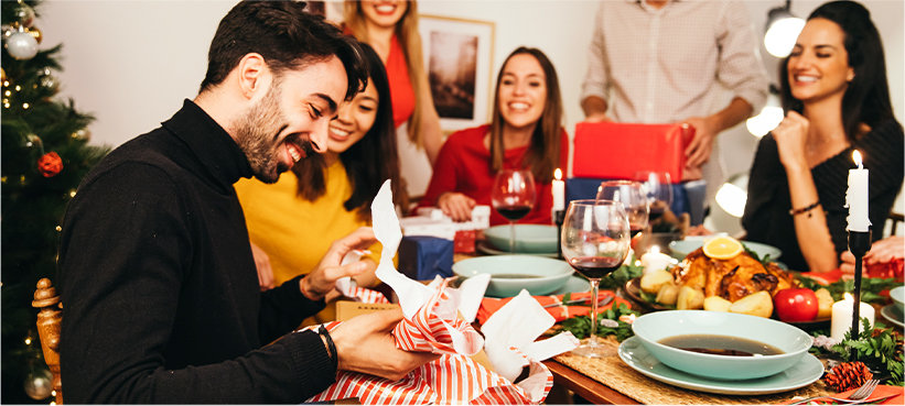 Friend opening gift at holiday dinner with friends.